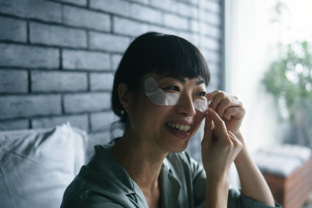 Woman applying under-eye patches to reduce wrinkles at home.